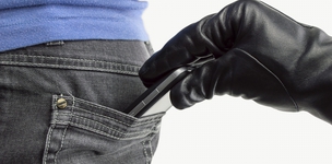 Mit schwarzem Handschuh geschützte Hand zieht einer Frau ein Smartphone aus der Gesäßtasche. (Bild: cunaplus / fotolia)