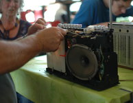 Ein junger Mann repariert ein altes aufgeschraubtes Radio. Bild: Goebel