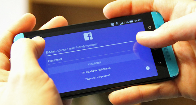 Zwei Hände halten ein Android-Smartphone, auf dem die Anmeldemaske der Facebook-App zu sehen ist. Bild: checked4you