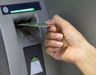 Eine Hand führt eine Plastikkarte in den Schlitz eines Geldautomaten ein. Bild: Khorzhevska / Fotolia.com