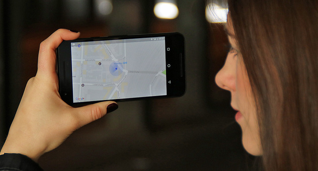 Eine junge Frau hält sich in einem dunklen Tunnel ein Smartphone mit Google Maps vors Gesicht. Bild: Verbraucherzentrale NRW