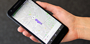 Auf dem Handy in der Hand einer Frau ist ein Stadtplan zu sehen. Eine violette Figur kennzeichnet den aktuellen Standort. Foto: checked4you.de