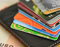 Stapel aus Bankkarten, Kreditkarten, Portmonee und 50-Euro-Schein. (Bild: ollegn / Fotolia)