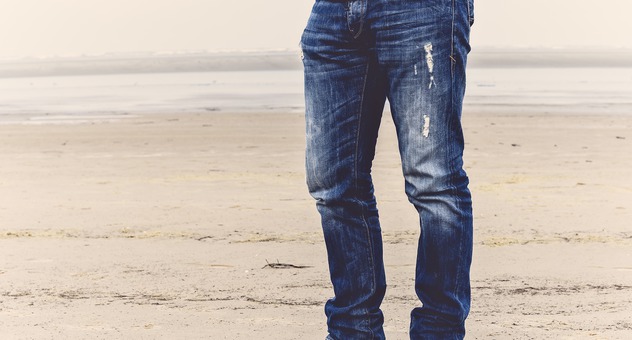 Mann mit abgewetzter Jeans am Strand