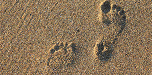 Zwei unterschiedlich große Fußabdrücke im Sand. (Foto: bluebudgie / pixabay.com)