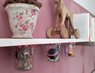 Weißes Regal mit angeschraubten Gläsern darunter an rosafarbener Wand. Foto: Katja Goebel