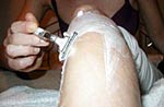 eine Frau rasiert sich das eingeschäumte Bein