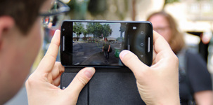 Ein Mann fotografiert mit seinem Smartphone mit etwas Entfernung eine Frau auf der Straße. Bild: checked4you
