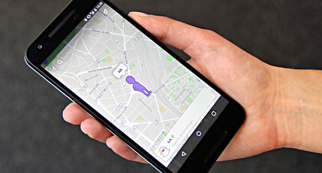 Auf dem Handy in der Hand einer Frau ist ein Stadtplan zu sehen. Eine violette Figur kennzeichnet den aktuellen Standort. Foto: checked4you.de