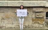 Eine junge schwarzhaarige Frau steht vor einer gemauerten Hauswand und hält eine Pappe mit der Aufschrift: "Was ist, wenn ..." in den Händen. Foto: checked4you