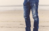 Mann mit abgewetzter Jeans am Strand
