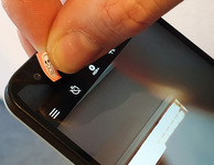 Zeigefinger und Daumen kleben einen kleinen Aufkleber mit Totenkopf auf die Selfie-Cam eines Smartphones. Bild: Verbraucherzentrale NRW