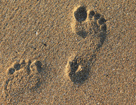 Zwei unterschiedlich große Fußabdrücke im Sand. (Foto: bluebudgie / pixabay.com)