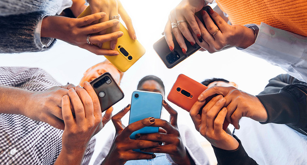 Jugendliche halten ihre Smartphones gemeinsam in die Mitte, von unten fotografiert. Foto: Davide Angelini / AdobeStock