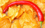 Eine rote Chilischote liegt auf gelben Kartoffelchips. Foto: Ralphs_Fotos / Pixabay.com